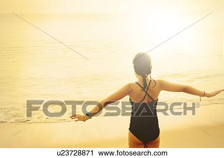 Rear view of girl (8-9) standing with arms raised View Large Photo Image Stock Image - Rear view of girl (8-9) standing with arms raised. Fotosearch