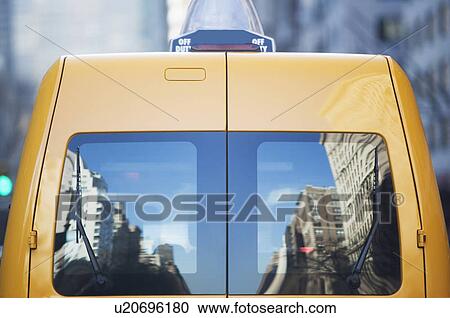 Stock Image - Reflection in rear window of yellow taxi. Fotosearch