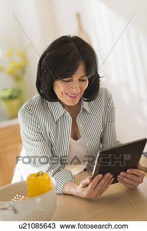 Senior woman holding digital tablet in kitchen View Large Photo Image Stock Image - Senior woman holding digital tablet in kitchen. Fotosearch