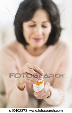 Stock Image - Senior woman holding pill bottle. Fotosearch