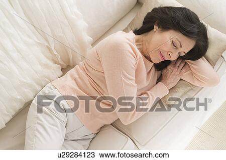 Stock Image - Senior woman napping on sofa. Fotosearch
