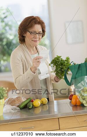 Senior woman reading shopping list in kitchen View Large Photo Image Stock Image - Senior woman reading shopping list in kitchen. Fotosearch