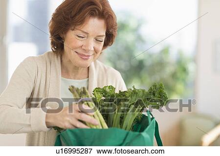Senior woman with groceries in kitchen View Large Photo Image Stock Photo - Senior woman with groceries in kitchen. Fotosearch
