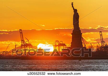 Stock Image - Silhouette of Statue of Liberty at sunset. Fotosearch