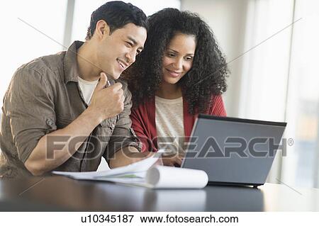 Smiling couple planning home ownership with model home View Large Photo Image Stock Photo - Smiling couple planning home ownership with model home. Fotosearch