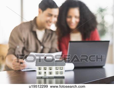 Smiling couple planning home ownership with model home View Large Photo Image Stock Photo - Smiling couple planning home ownership with model home. Fotosearch