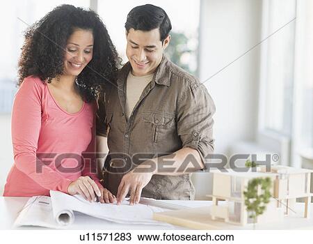 Stock Image - Smiling couple with model home. Fotosearch