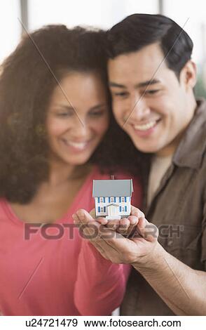 Stock Photo - Smiling couple with model home. Fotosearch