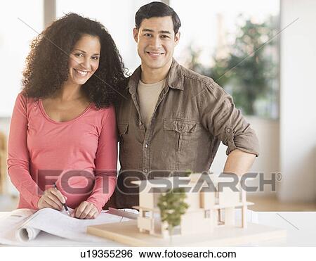 Smiling couple with model home View Large Photo Image Stock Photograph - Smiling couple with model home. Fotosearch
