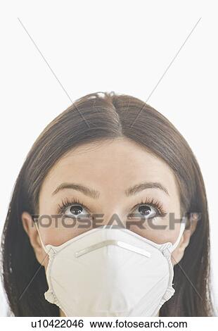 Stock Photograph - Studio portrait of woman wearing flu mask. Fotosearch