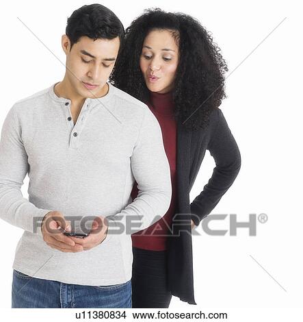 Picture - Studio shot of young couple looking at cell phone. Fotosearch