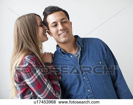 Studio Shot portrait of young couple whispering and smiling View Large Photo Image Stock Photo - Studio Shot portrait of young couple whispering and smiling. Fotosearch