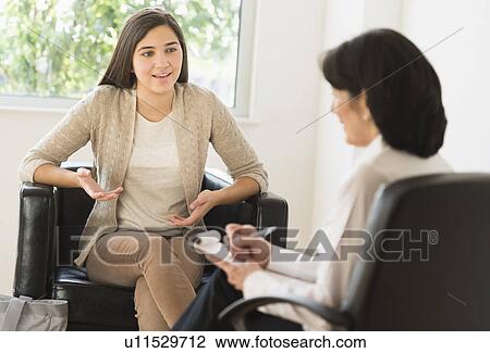 Stock Image - Teenage girl (16-17) talking to therapist. Fotosearch