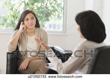 Stock Image - Teenage girl (16-17) talking to therapist. Fotosearch