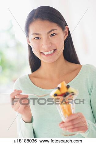 Teenage girl eating fruit dessert View Large Photo Image Stock Photograph - Teenage girl eating fruit dessert. Fotosearch