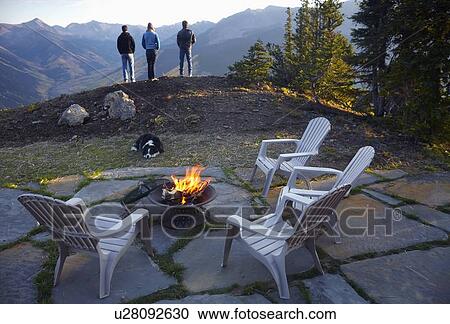 Three people standing near fire pit looking at landscape View Large Photo Image Stock Image - Three people standing near fire pit looking at landscape . Fotosearch