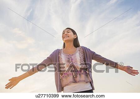 Upward view of teenage girl ( 16-17 years) standing with arms raised View Large Photo Image Stock Photo - Upward view of teenage girl ( 16-17 years) standing with arms raised. Fotosearch
