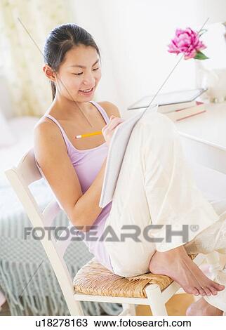 Stock Image - View of teenage girl ( 16-17 years) studying at home. Fotosearch