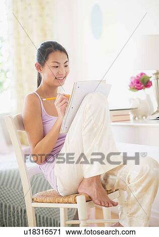 Stock Image - View of teenage girl (16-17 years) studying at home. Fotosearch