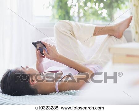 View of Teenage girl ( 16-17 years) using mobile phone lying on bed View Large Photo Image Stock Photography - View of Teenage girl ( 16-17 years) using mobile phone lying on bed. Fotosearch