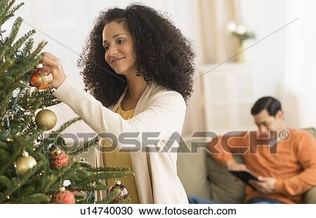 Stock Image - Woman decorating Christmas tree. Fotosearch