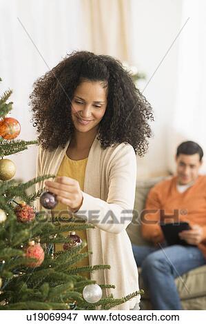 Woman decorating Christmas tree View Large Photo Image Stock Photo - Woman decorating Christmas tree. Fotosearch