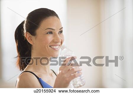 Picture - Woman drinking water in gym. Fotosearch