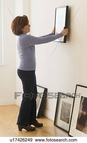 Woman hanging picture on wall View Large Photo Image Stock Photo - Woman hanging picture on wall. Fotosearch