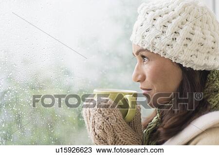 Stock Image - Woman in warm clothes holding mug. Fotosearch