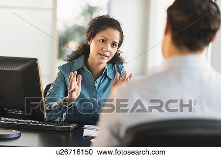 Stock Image - Woman interviewing man at desk. Fotosearch