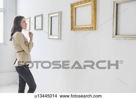 Picture - Woman looking at blank pictures in art gallery. Fotosearch