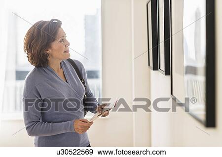 Stock Photo - Woman looking at picture in art museum. Fotosearch