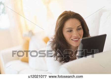 Woman on sofa using tablet pc View Large Photo Image Stock Photo - Woman on sofa using tablet pc. Fotosearch