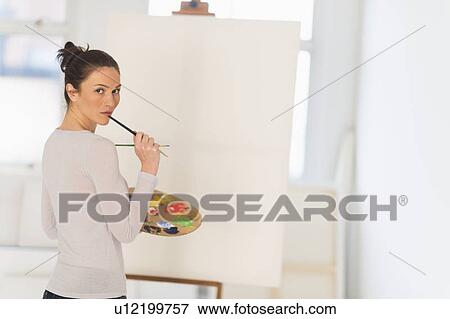Stock Photo - Woman painting at easel. Fotosearch