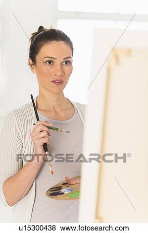 Stock Photo - Woman painting at easel. Fotosearch