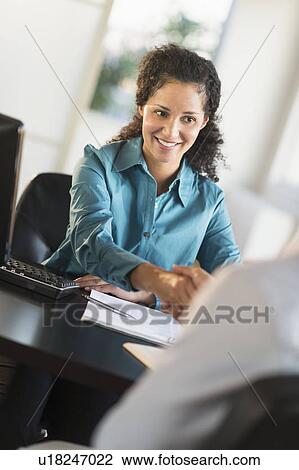Woman shaking hand with man at desk View Large Photo Image Stock Image - Woman shaking hand with man at desk. Fotosearch