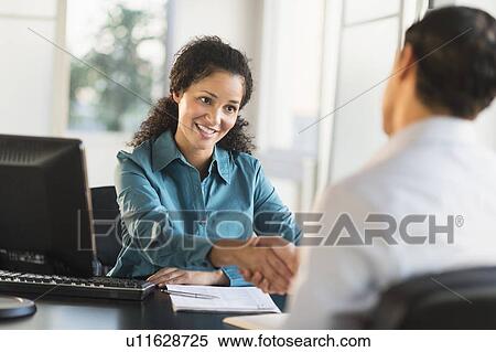 Woman shaking hand with man at desk View Large Photo Image Stock Photography - Woman shaking hand with man at desk. Fotosearch