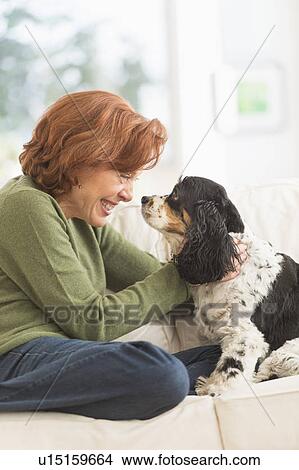Picture - Woman sitting on sofa with dog. Fotosearch