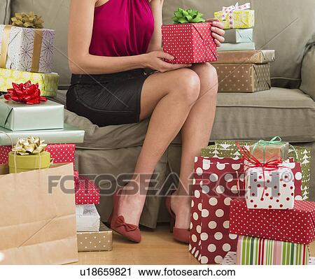 Woman surrounded with christmas gifts sitting on sofa View Large Photo Image Stock Image - Woman surrounded with christmas gifts sitting on sofa. Fotosearch