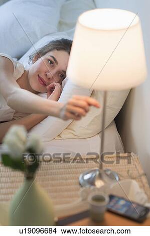 Picture - Woman turning off lamp. Fotosearch