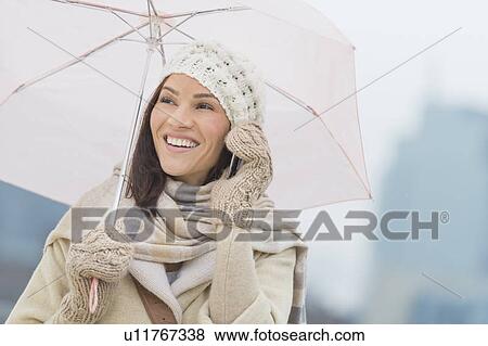 Stock Photo - Woman with umbrella using phone. Fotosearch