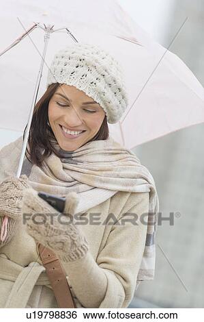 Woman with umbrella using phone View Large Photo Image Stock Photograph - Woman with umbrella using phone. Fotosearch
