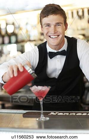Stock Image - Young bartender pouring cocktail . Fotosearch