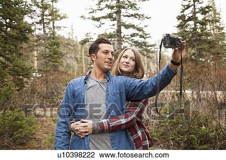 Young couple self photographing in non-urban scene View Large Photo Image Stock Image - Young couple self photographing in non-urban scene. Fotosearch