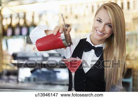 Stock Photo - Young female bartender pouring cocktail . Fotosearch