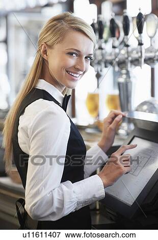 Stock Photo - Young waitress using computer at restaurant counter. Fotosearch
