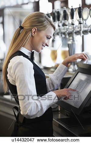 Stock Photo - Young waitress using computer at restaurant counter. Fotosearch