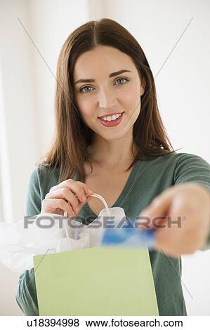Stock Photo - Young woman holding shopping bag and credit card. Fotosearch