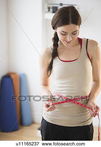Stock Photo - Young woman measuring waist. Fotosearch