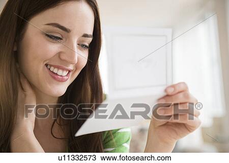 Stock Image - Young woman reading letter. Fotosearch